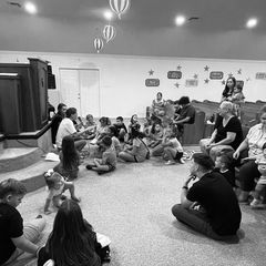 Children sitting in a circle on the floor of the fellowship hall