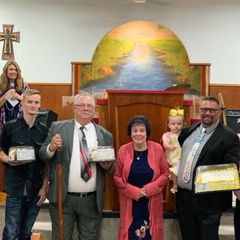 Men of the church holding gifts in front of the pulpit