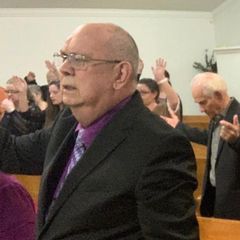 A man praying during worship while others raise their hands