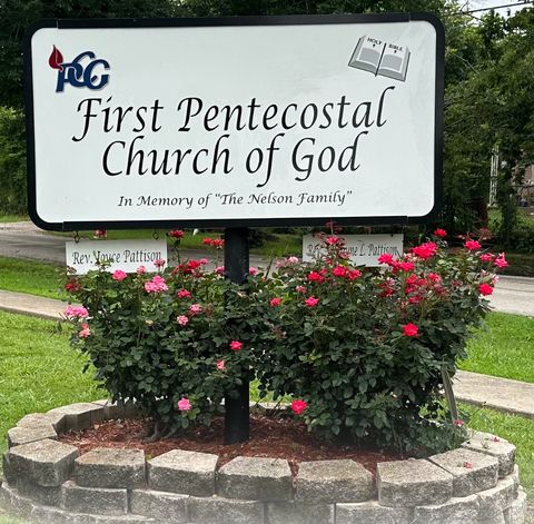 The church sign reading In Memory of The Nelson Family, with red rose bushes in front