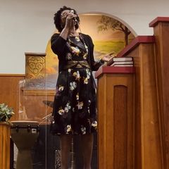 A woman singing into a microphone beside the pulpit